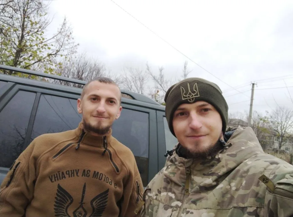 Двоє чоловіків у військовому одязі біля автомобіля