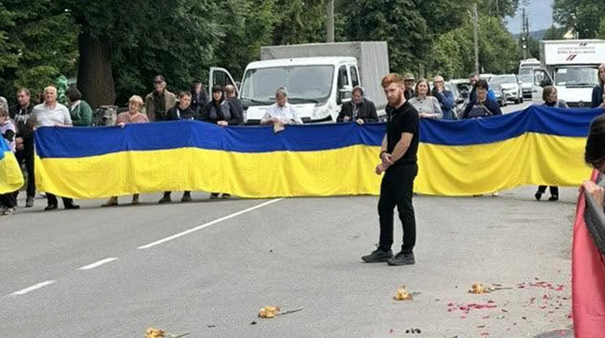 Люди тримають великий прапор України на дорозі
