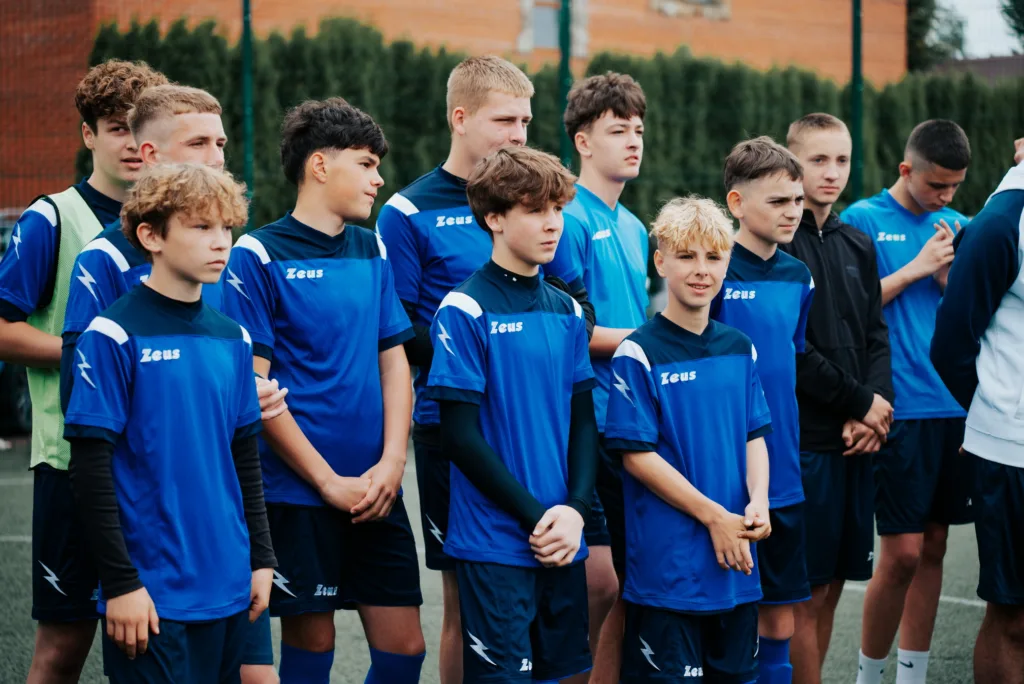 Молодіжна футбольна команда у синій формі на полі