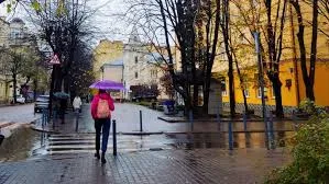 Людина з парасолькою йде мокрою міською вулицею