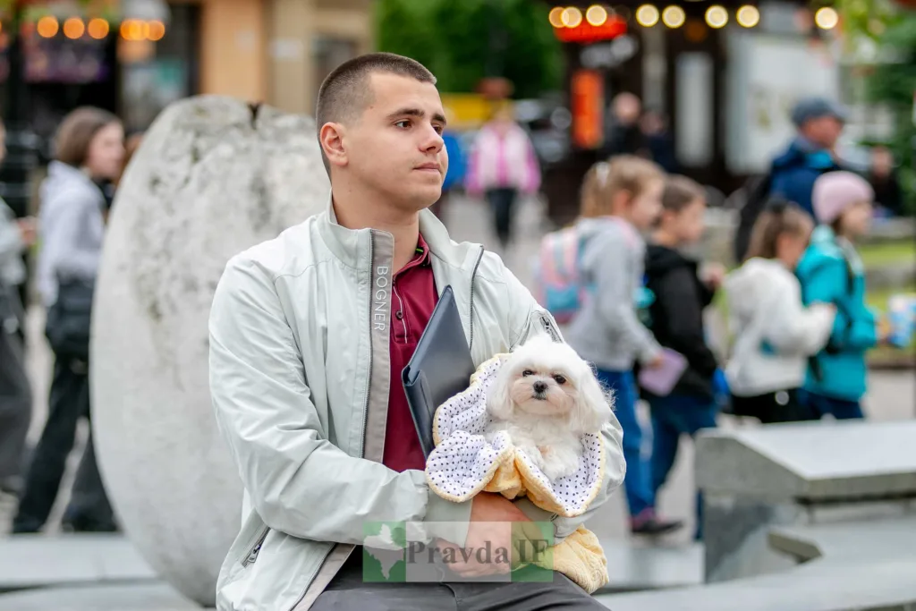 Чоловік тримає маленького білого собаку на вулиці