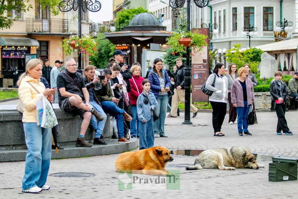 Люди в місті спостерігають за вуличною подією