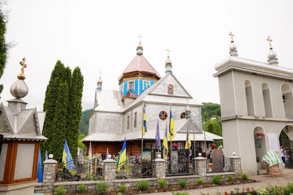 Українська церква з прапорами у гірському селі