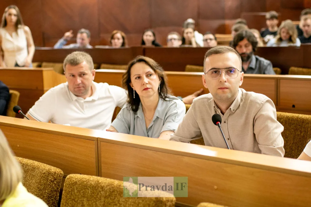 Люди на засіданні в залі з мікрофонами