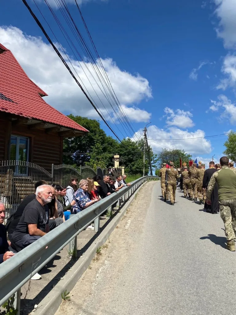 Люди проводжають військових на сільській дорозі
