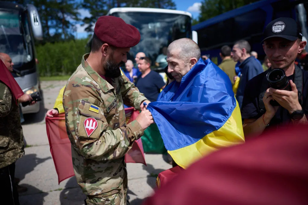 Військовий накриває прапором України звільненого полоненого