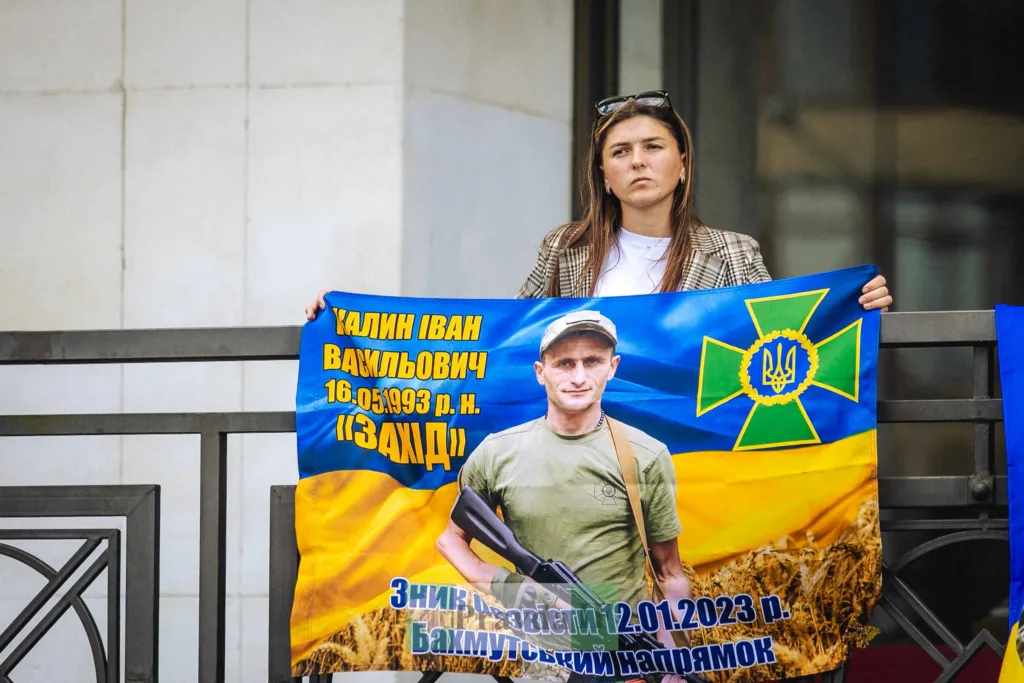 Жінка тримає плакат із фотографією українського військового