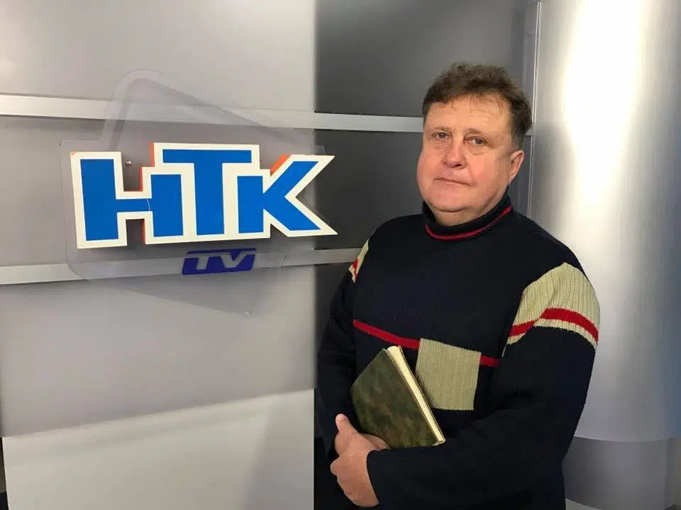 Чоловік біля логотипу телеканалу НТК