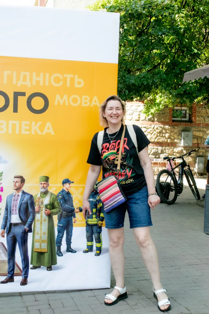 Жінка усміхається біля жовтого банера на вулиці