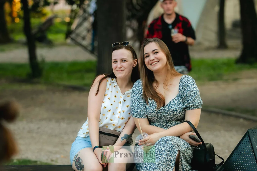 Дві жінки посміхаються, сидячи на лавці в парку
