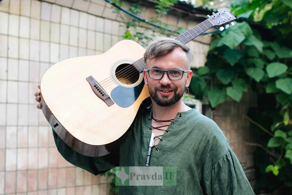 Чоловік з гітарою на плечі на вулиці