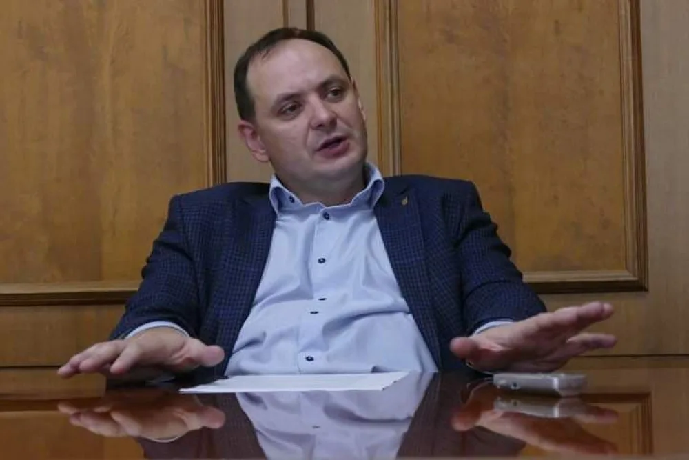 Чоловік у костюмі сидить за столом