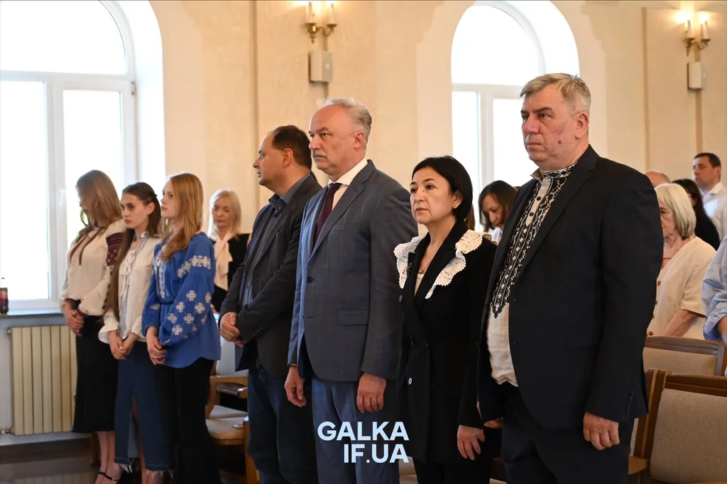 Люди стоять під час урочистого заходу в залі