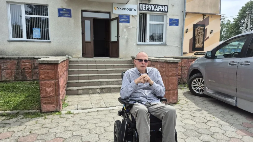Чоловік на інвалідному візку перед будівлею Укрпошти