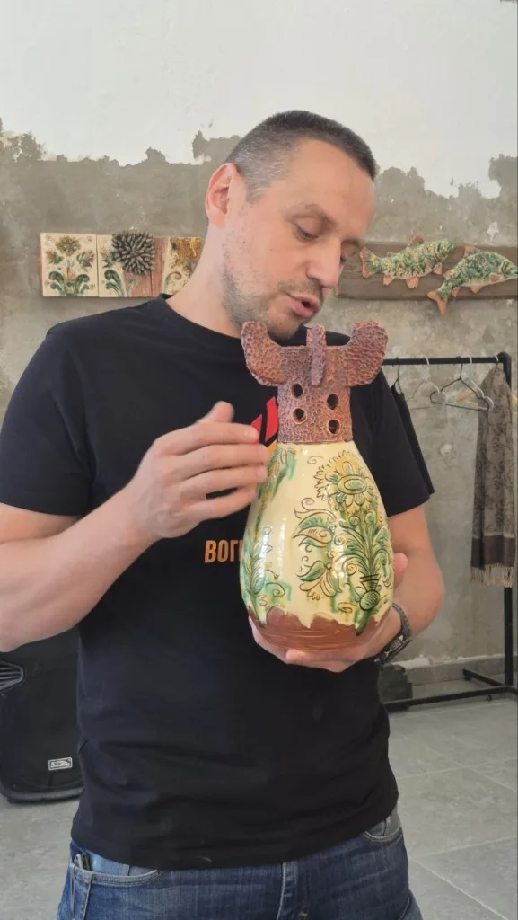 Чоловік тримає керамічний глечик із візерунками