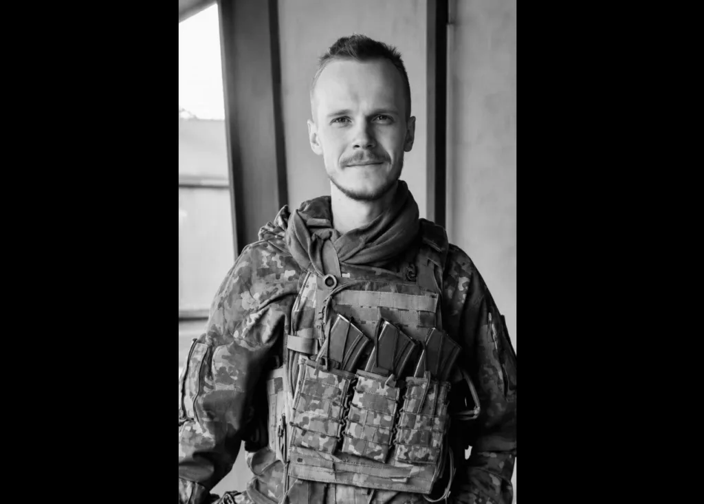 Український військовий у камуфляжі стоїть усередині будівлі