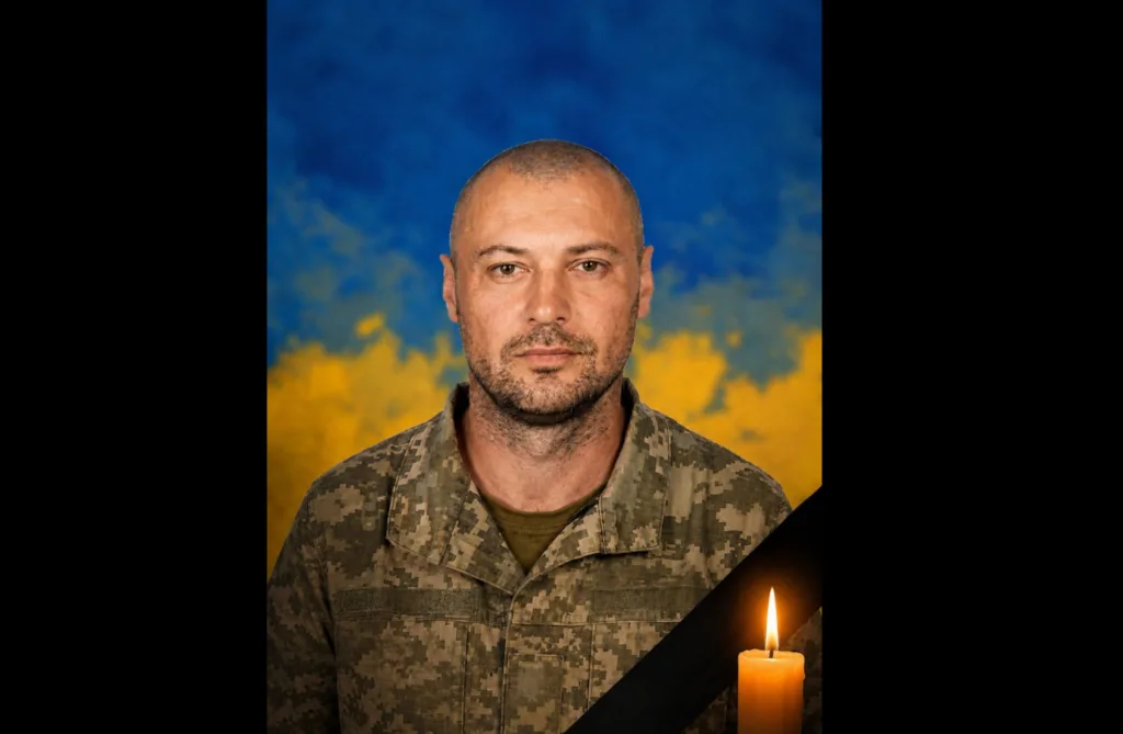 Український військовий на тлі прапора з траурною свічкою