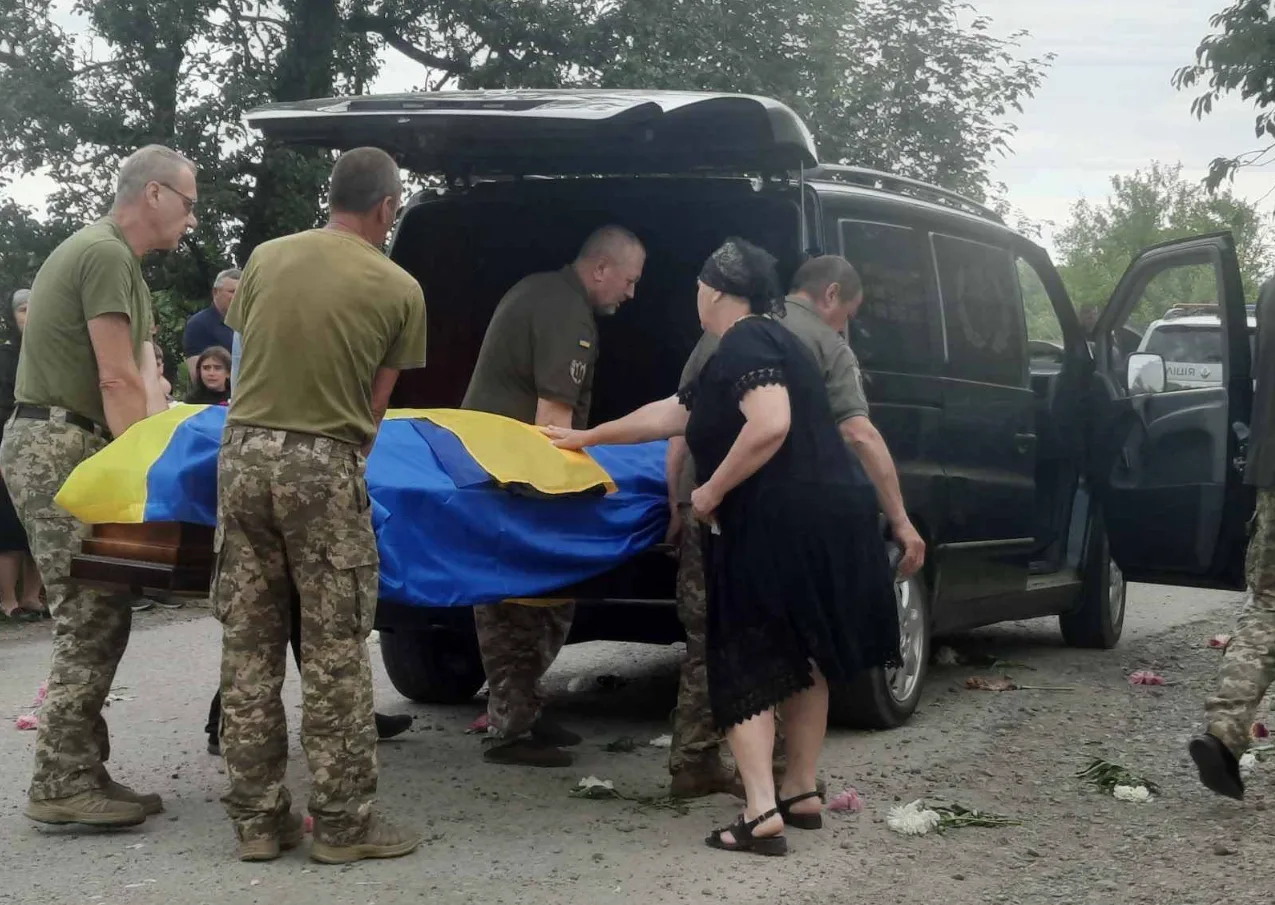 Військові несуть труну, накриту українським прапором
