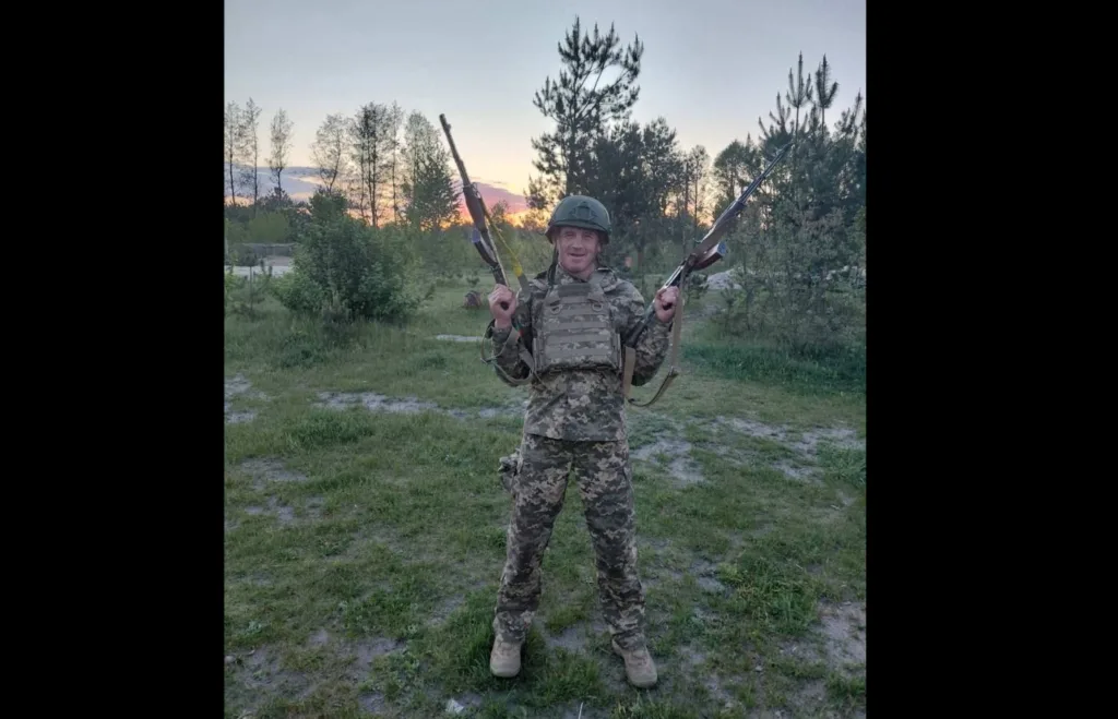 Військовий у камуфляжі тримає дві гвинтівки на природі