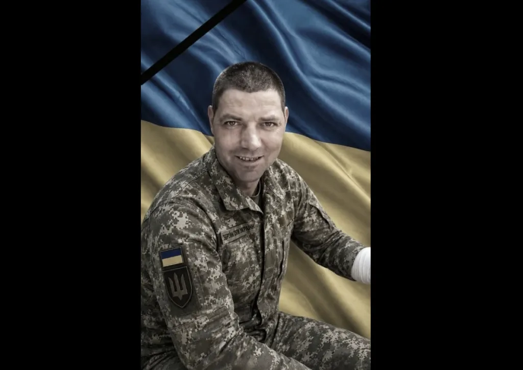 Український військовий перед прапором України