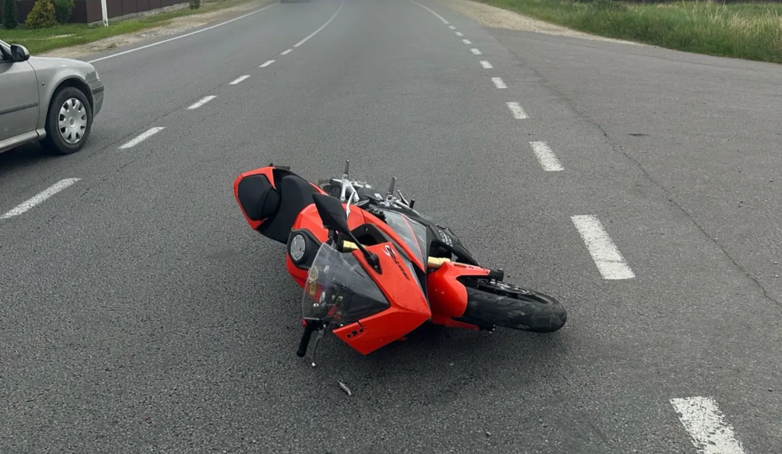 Червоний мотоцикл лежить на асфальті після аварії