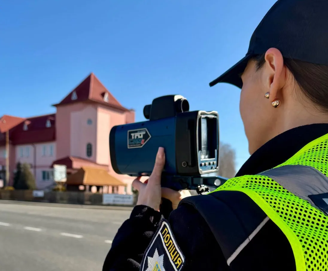 Поліцейська вимірює швидкість руху автомобілів
