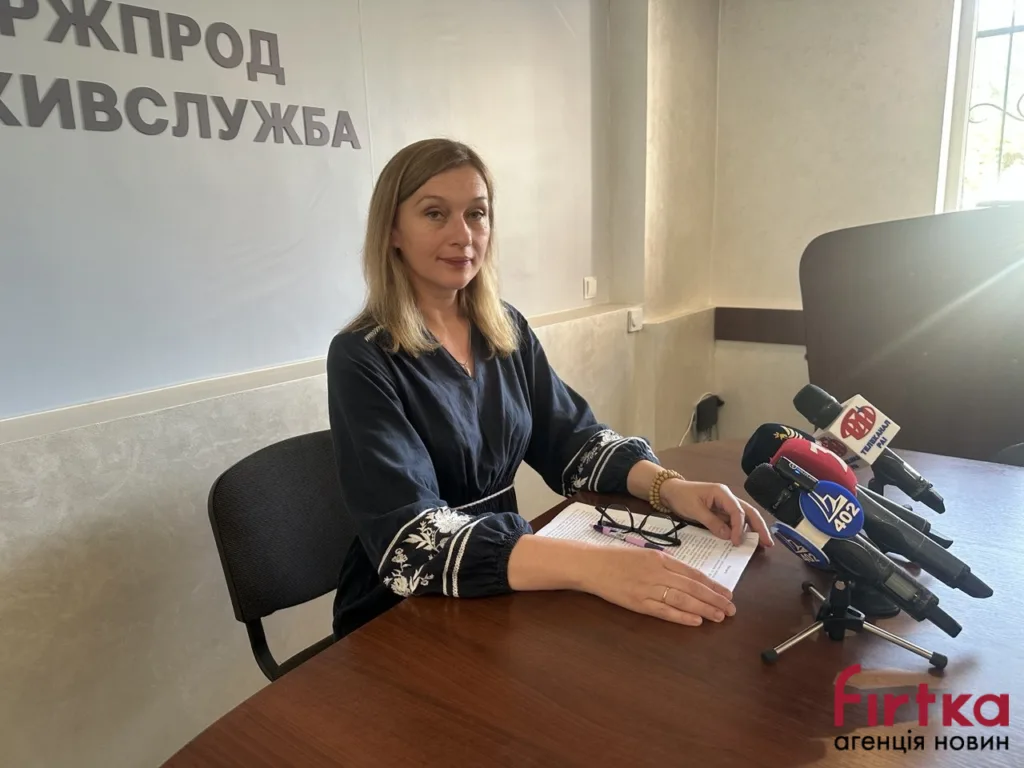 Жінка на пресконференції за столом з мікрофонами