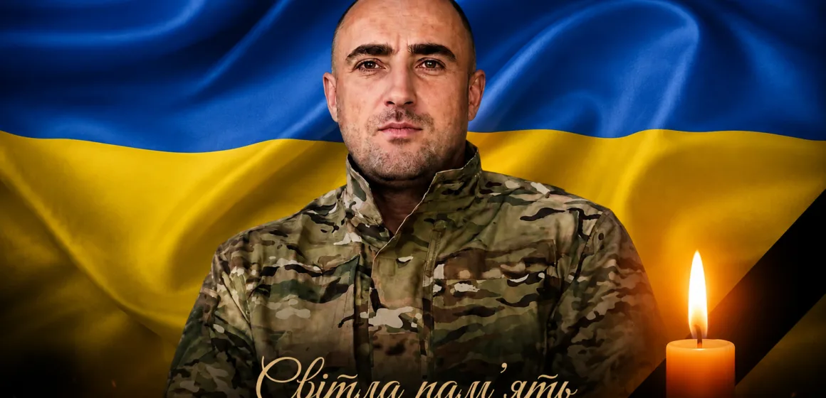 Український військовий перед прапором України з свічкою