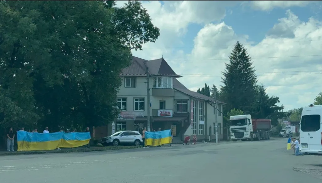 Люди тримають великий прапор України біля дороги