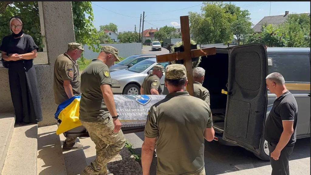 Військові несуть труну, накриту українським прапором