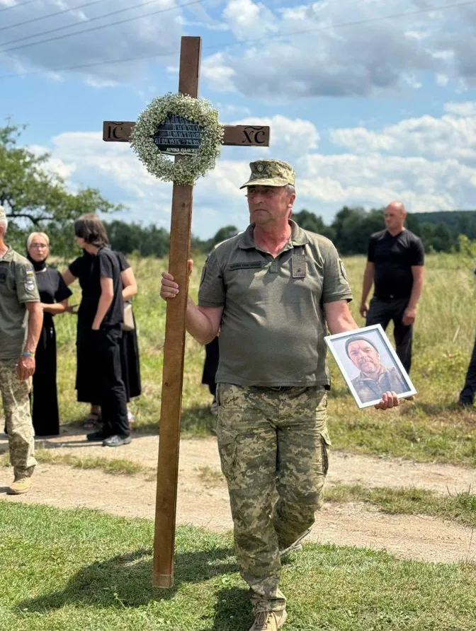 Військовий несе хрест і фотографію загиблого героя