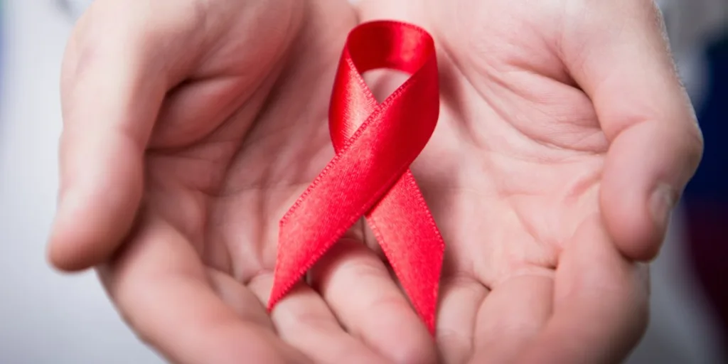 Червона стрічка у долонях символ підтримки ВІЛ