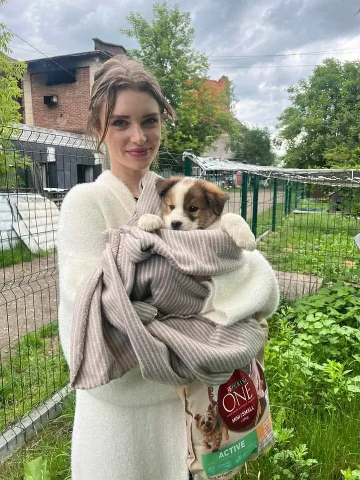 Жінка тримає цуценя, загорнуте в ковдру