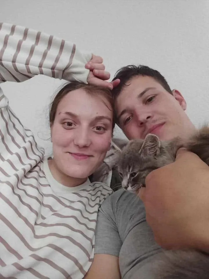 Пара обіймає кота та посміхається