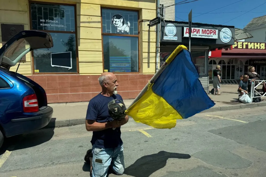 Чоловік на колінах тримає прапор України