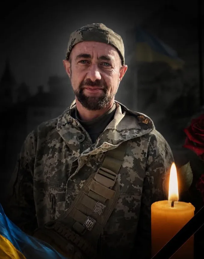Український військовий у формі з прапором і свічкою