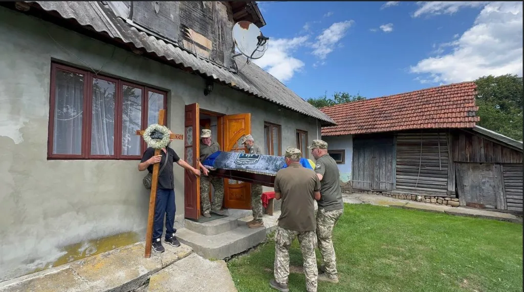 Військові несуть труну з будинку в селі