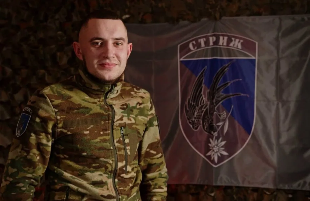 Військовий у камуфляжі перед прапором Стриж