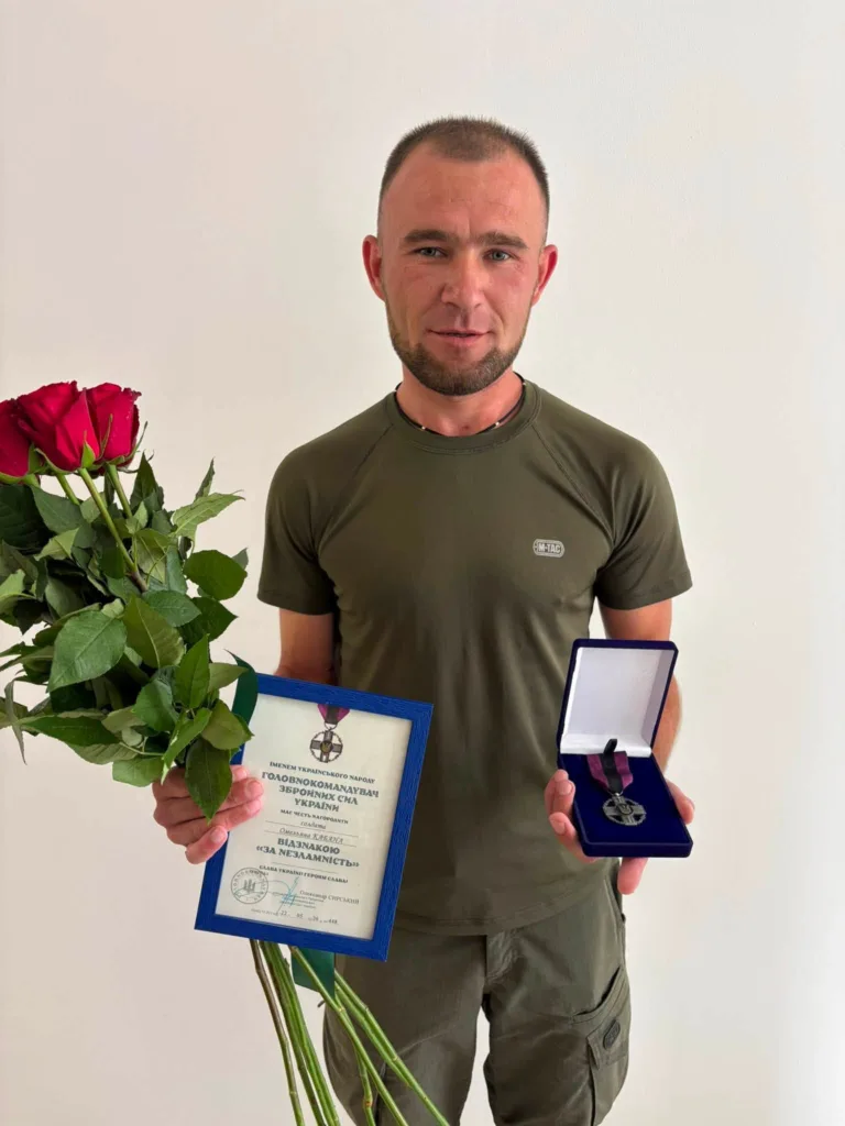Чоловік з квітами, грамотою та медаллю