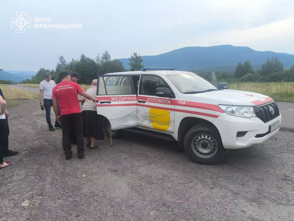 Рятувальники допомагають жінці біля медичної машини