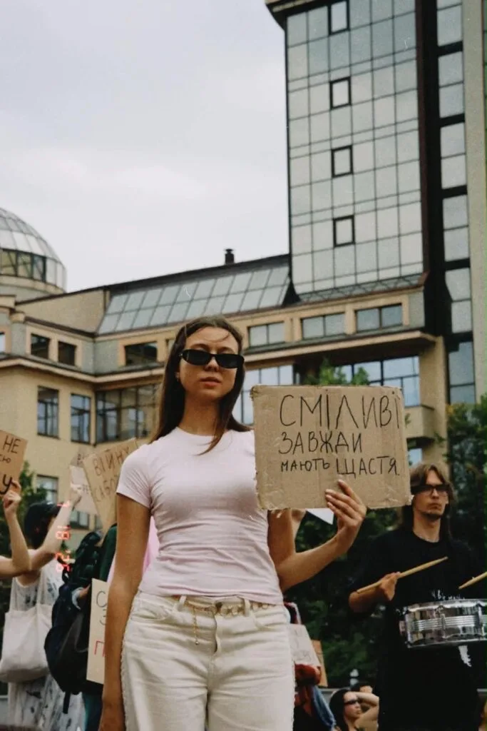 Жінка тримає плакат на мирному протесті