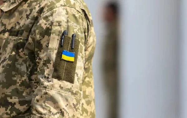 Український військовий у камуфляжі з прапором України