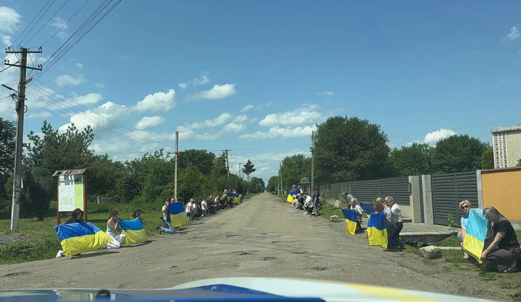 Люди з українськими прапорами вздовж дороги