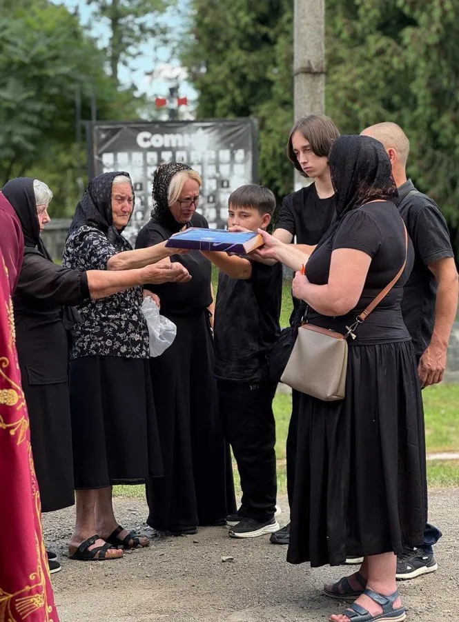 Люди в чорному одязі тримають прапор на церемонії