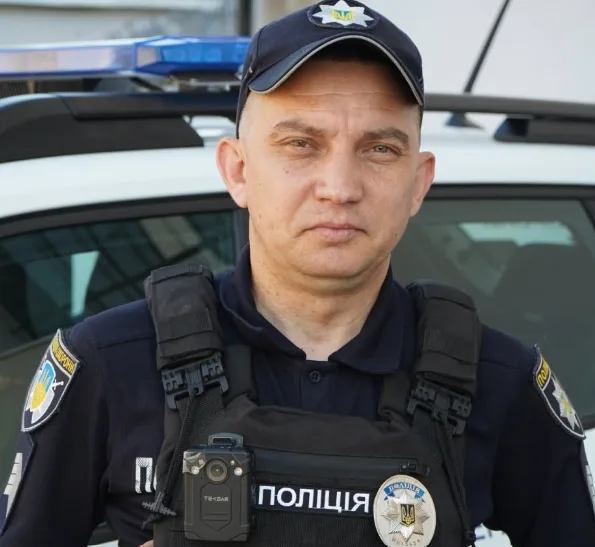 Офіцер поліції стоїть біля патрульного авто