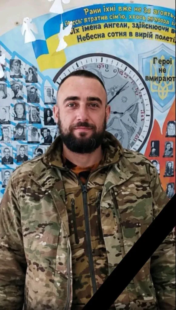 Військовий у камуфляжі перед меморіальною стіною
