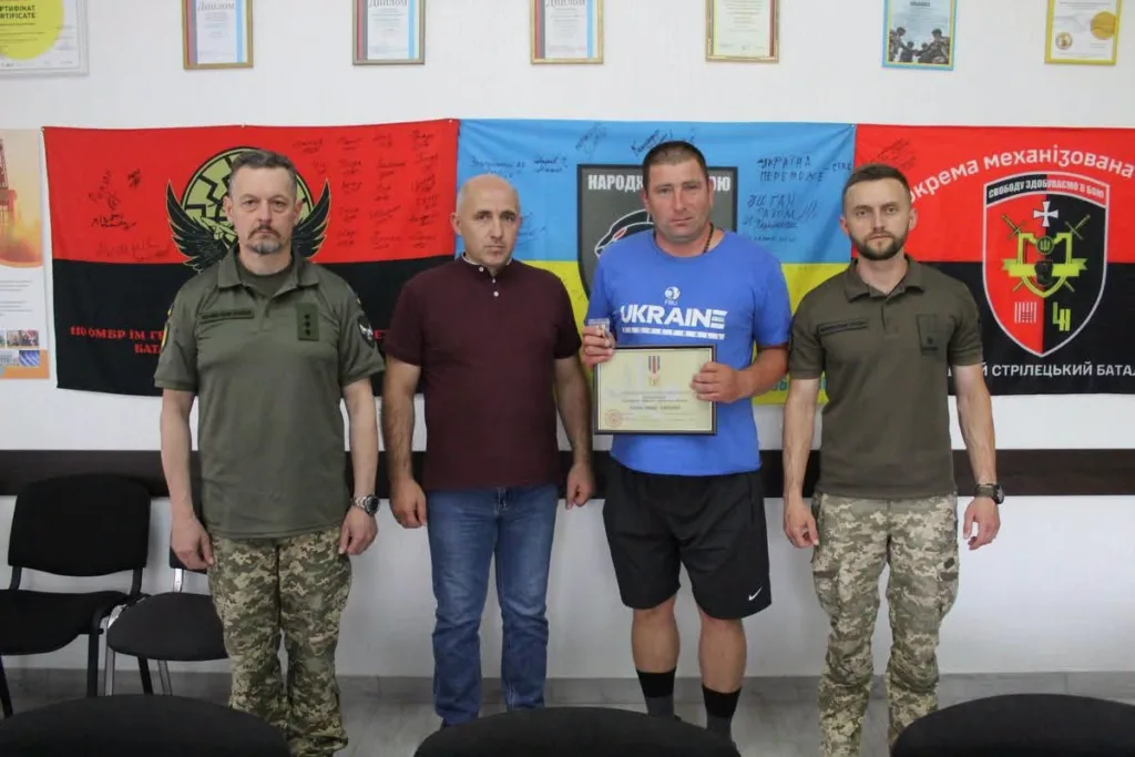 Воїни отримують нагороду перед прапорами України