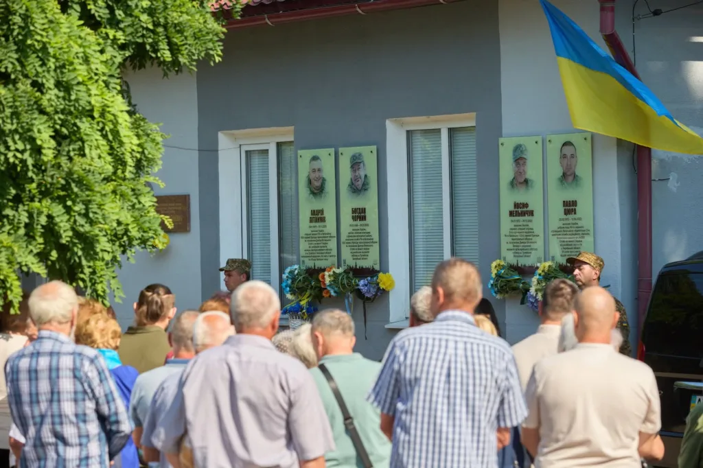 Люди вшановують загиблих воїнів біля меморіальних дошок