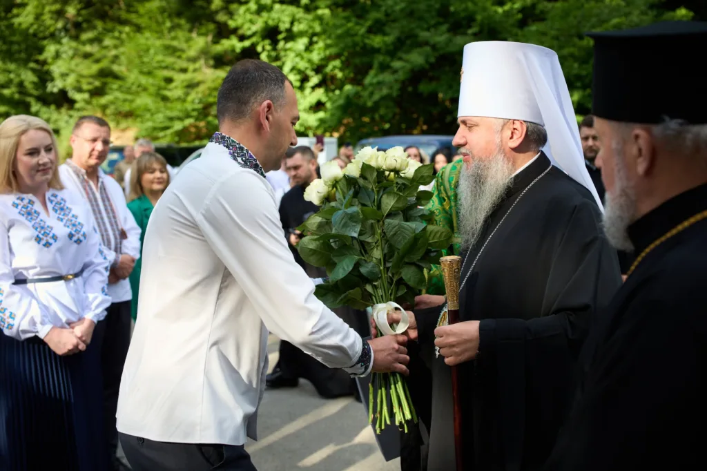 Чоловік дарує квіти священнику на церемонії