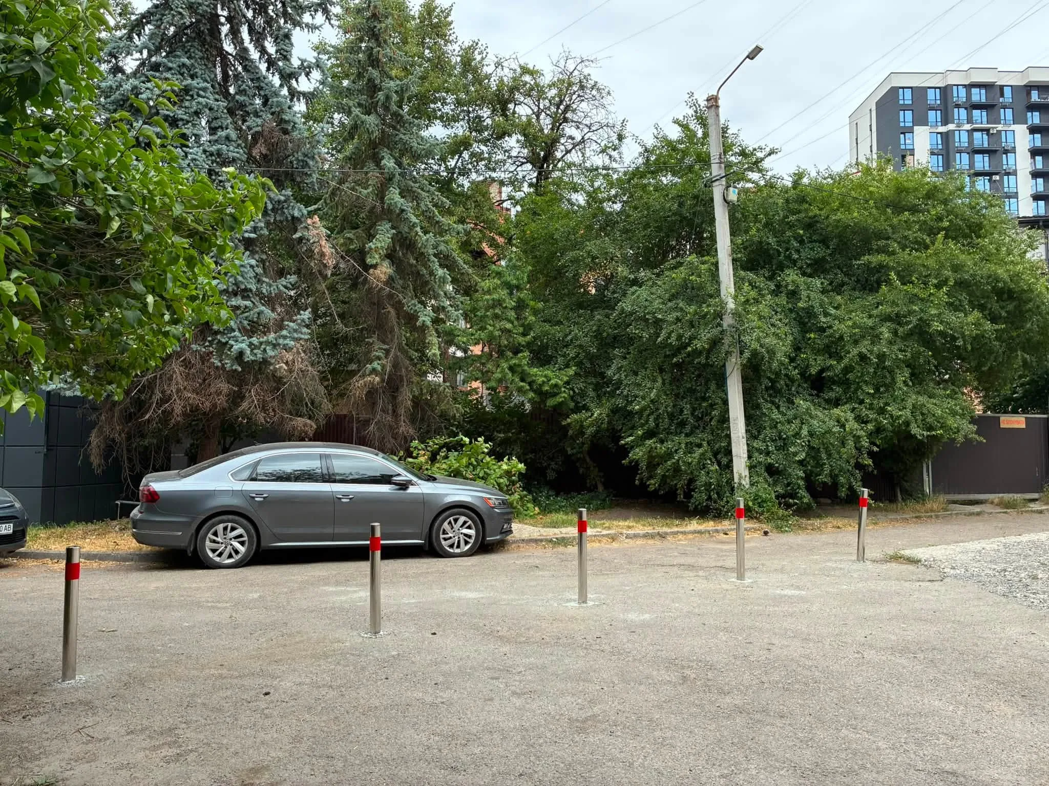 Сірий автомобіль припаркований біля дерев та будинку